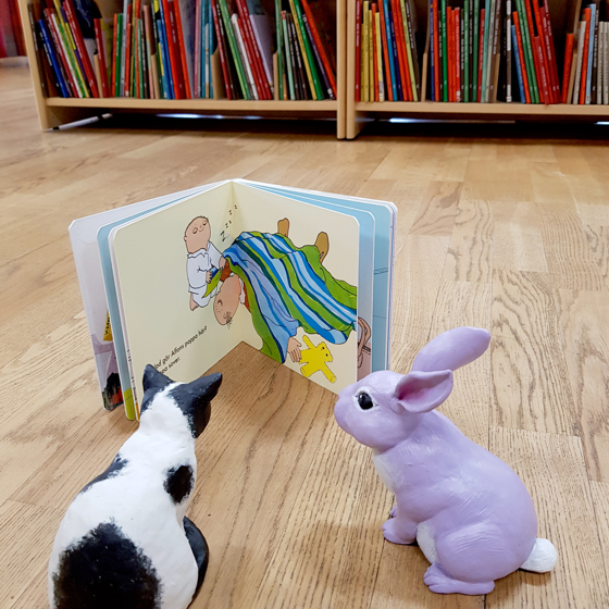 Katten och kaninen läser en bok tillsammans.