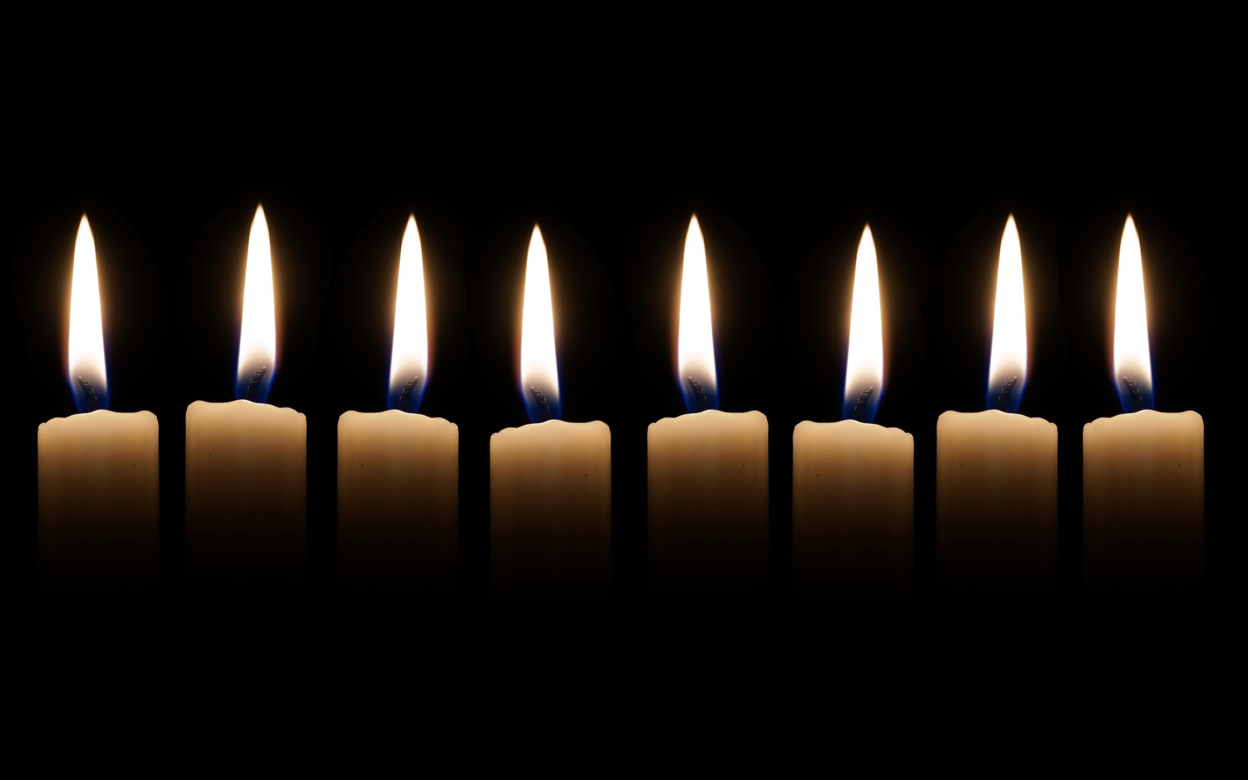 Åtta tända ljus som står på rad.